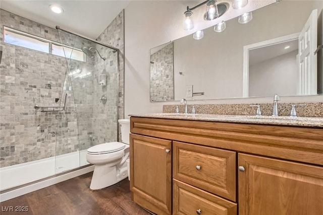 full bathroom featuring a sink, toilet, wood finished floors, and a shower stall