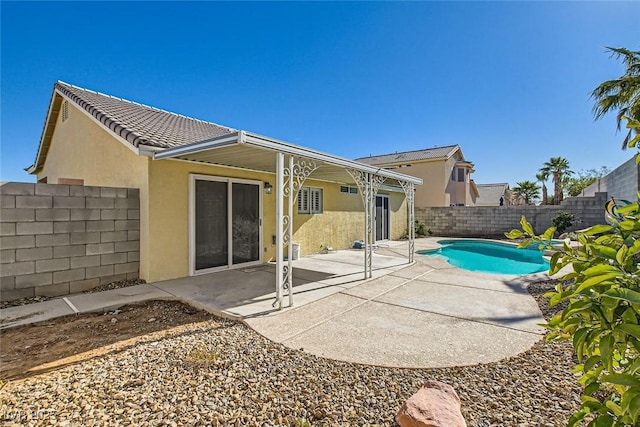 rear view of property featuring stucco siding, a patio, a fenced backyard, a fenced in pool, and a tiled roof