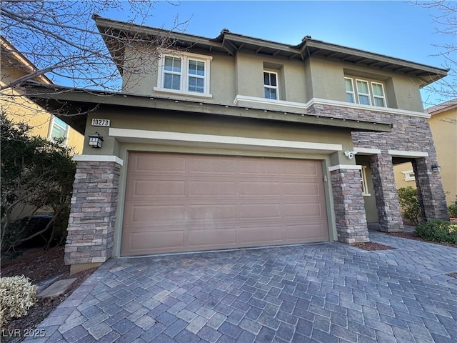 prairie-style house with a garage, stone siding, decorative driveway, and stucco siding