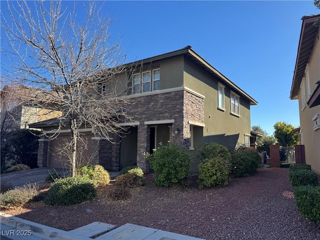 view of front of home featuring a gate, stone siding, concrete driveway, and stucco siding