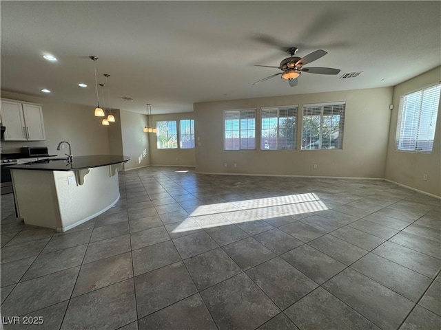 interior space featuring white cabinetry, dark tile patterned flooring, pendant lighting, and a healthy amount of sunlight