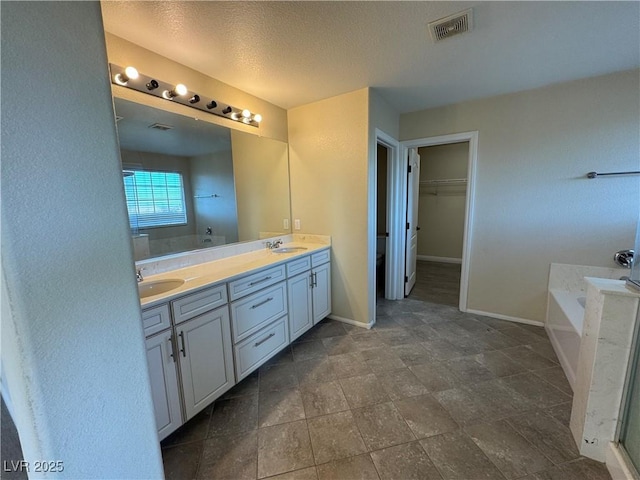 bathroom with vanity, a tub, and a textured ceiling