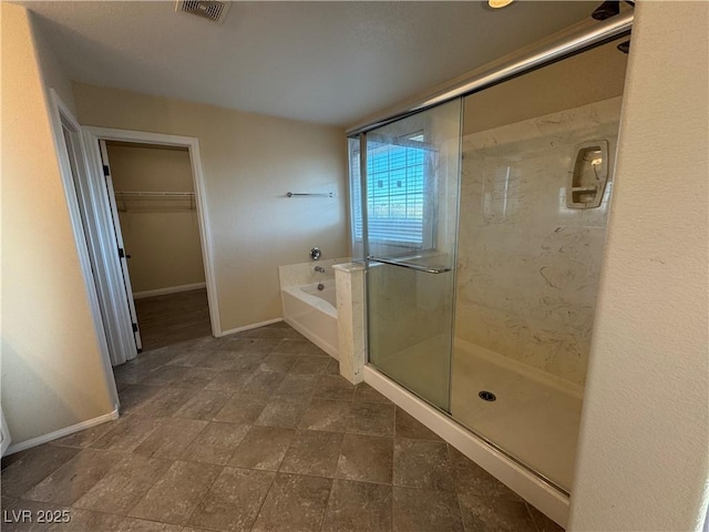 bathroom with a bath, a stall shower, visible vents, and baseboards