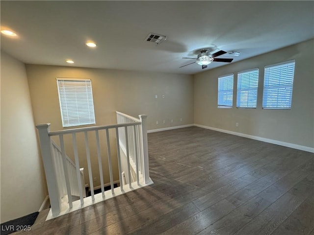 unfurnished room featuring baseboards, visible vents, dark wood finished floors, and recessed lighting