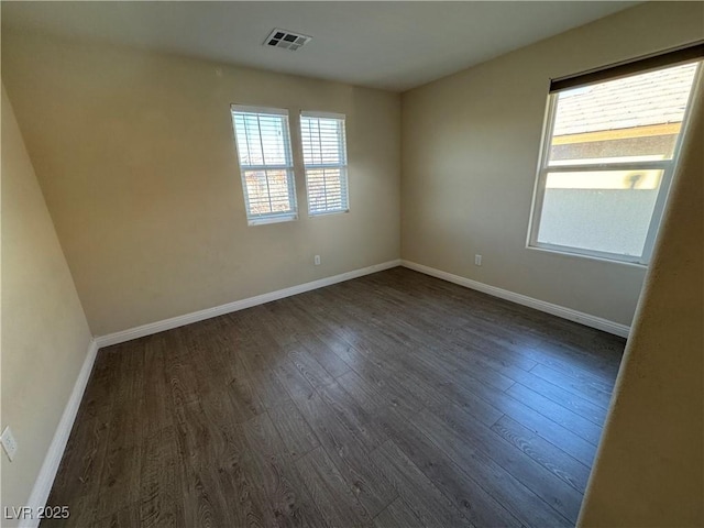 spare room with baseboards, visible vents, and dark wood-type flooring