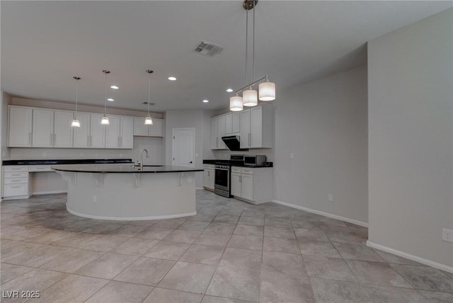 10273 Aragon Crown Rd, Las Vegas, NV 89135 - kitchen with dark countertops, stainless steel range with gas stovetop, baseboards, recessed lighting, and an island with sink