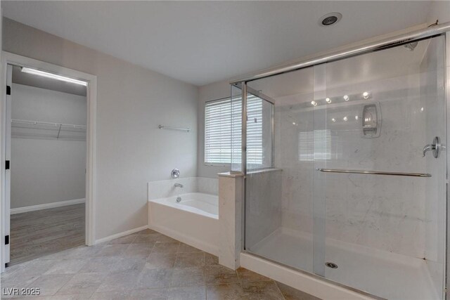 10273 Aragon Crown Rd, Las Vegas, NV 89135 - bathroom featuring a garden tub, a stall shower, a spacious closet, baseboards, and tile patterned flooring