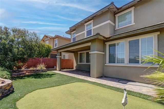 10273 Aragon Crown Rd, Las Vegas, NV 89135 - back of house with stucco siding, a putting area, fence, and a patio