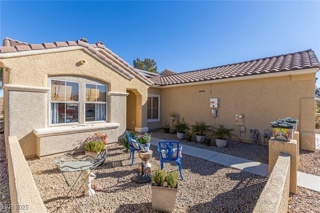 back of property with stucco siding, a patio, solar panels, and a tiled roof