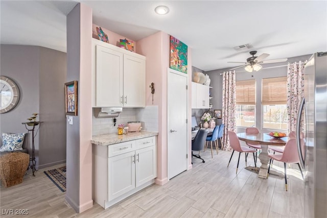 kitchen with light hardwood / wood-style flooring, stainless steel fridge, ceiling fan, white cabinetry, and tasteful backsplash