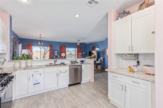 kitchen with kitchen peninsula, pendant lighting, sink, white cabinets, and stainless steel appliances