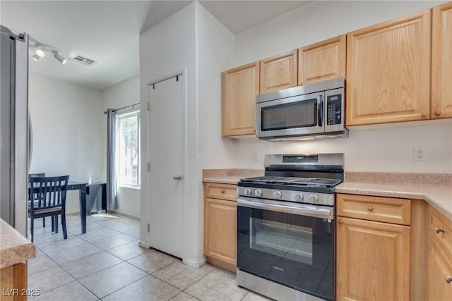 kitchen featuring light tile patterned floors, light brown cabinets, and appliances with stainless steel finishes