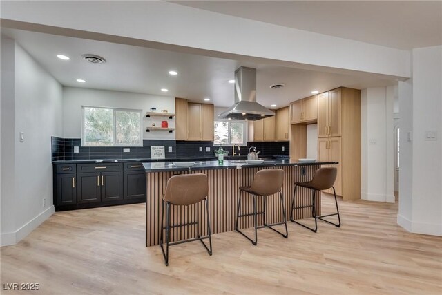 kitchen with a healthy amount of sunlight, island range hood, light hardwood / wood-style flooring, and light brown cabinets