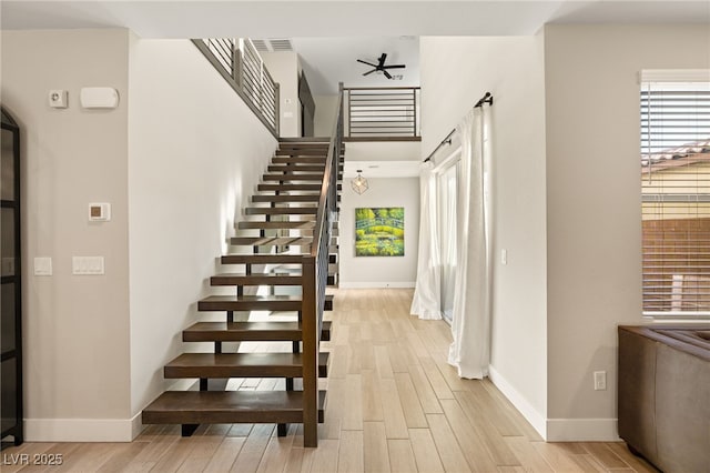 stairs with hardwood / wood-style floors and ceiling fan