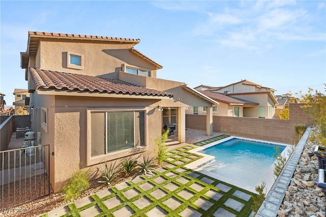 rear view of house featuring a fenced in pool and a patio area