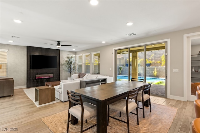 dining space featuring ceiling fan, light hardwood / wood-style floors, and a fireplace