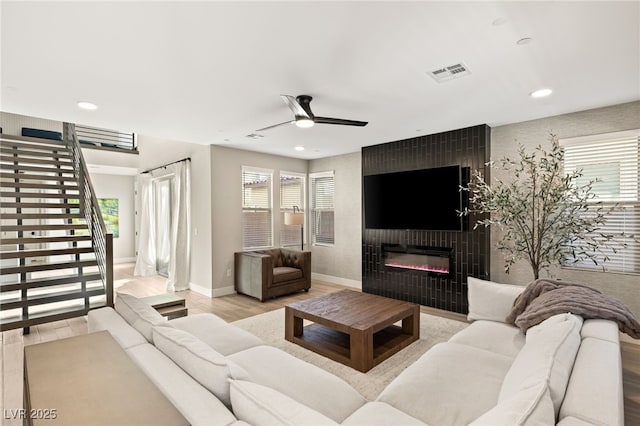 living room featuring a fireplace, light wood-type flooring, and ceiling fan