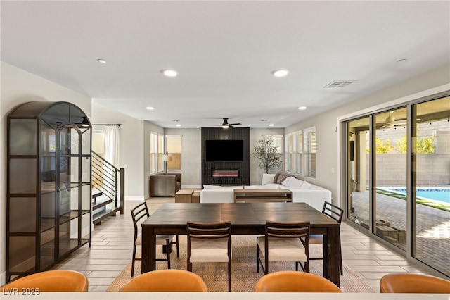 dining area featuring ceiling fan and a fireplace