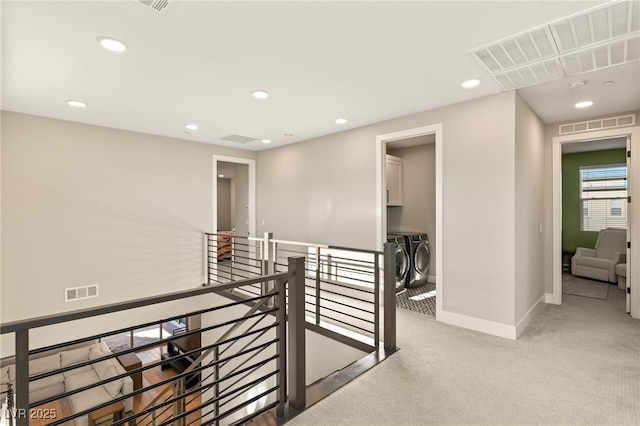 hall featuring washing machine and clothes dryer and light colored carpet