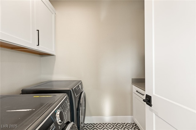 clothes washing area featuring cabinets and washer and clothes dryer