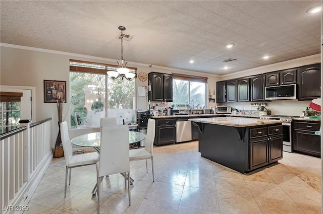 kitchen with hanging light fixtures, crown molding, a kitchen island, and appliances with stainless steel finishes