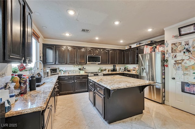 kitchen with crown molding, appliances with stainless steel finishes, a center island, light stone countertops, and light tile patterned flooring