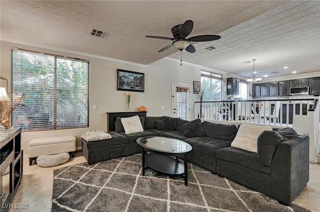 tiled living room featuring crown molding, a healthy amount of sunlight, ceiling fan with notable chandelier, and a textured ceiling