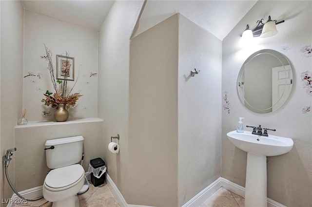 bathroom featuring tile patterned flooring, vaulted ceiling, sink, and toilet