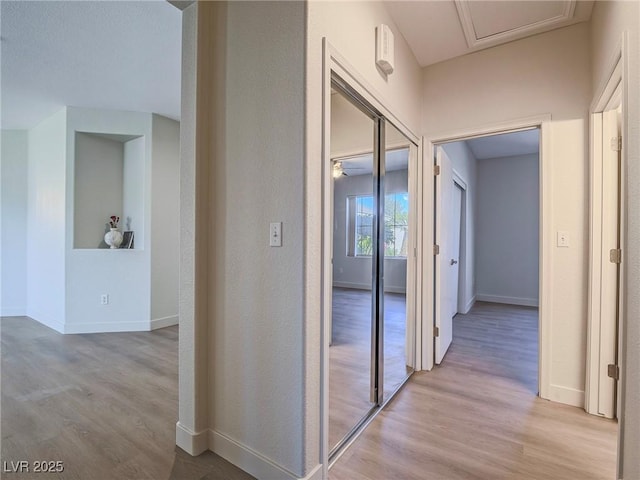 corridor with baseboards and light wood-style flooring