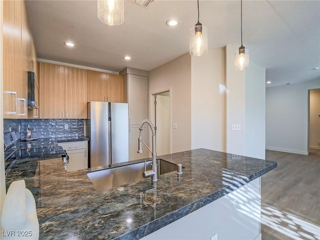 kitchen with tasteful backsplash, freestanding refrigerator, wood finished floors, electric range, and a sink