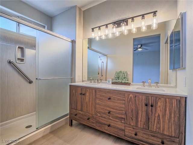 full bathroom featuring double vanity, a stall shower, wood finished floors, and a sink