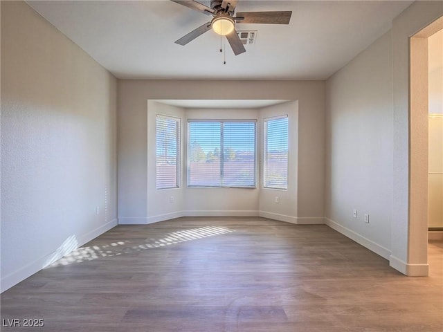 empty room with visible vents, baseboards, and wood finished floors