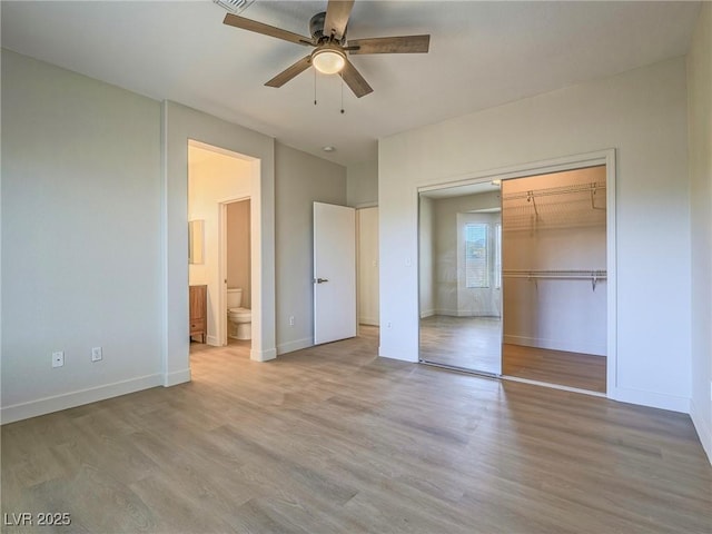 unfurnished bedroom featuring connected bathroom, ceiling fan, baseboards, wood finished floors, and a closet