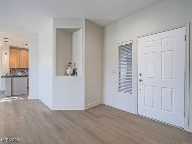 foyer entrance with baseboards and light wood-type flooring