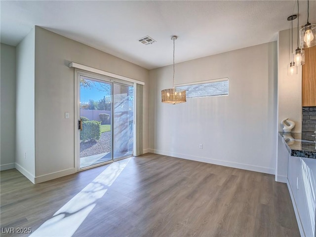 unfurnished dining area with visible vents, baseboards, and wood finished floors