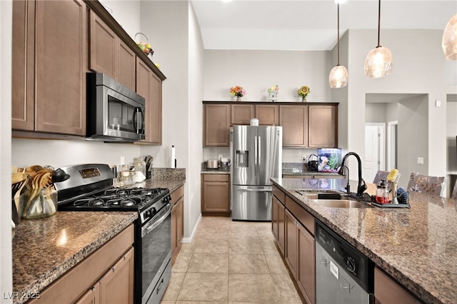 kitchen featuring pendant lighting, stainless steel appliances, dark stone countertops, sink, and light tile patterned flooring