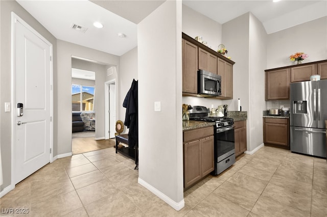 kitchen featuring light tile patterned floors, appliances with stainless steel finishes, and dark stone counters