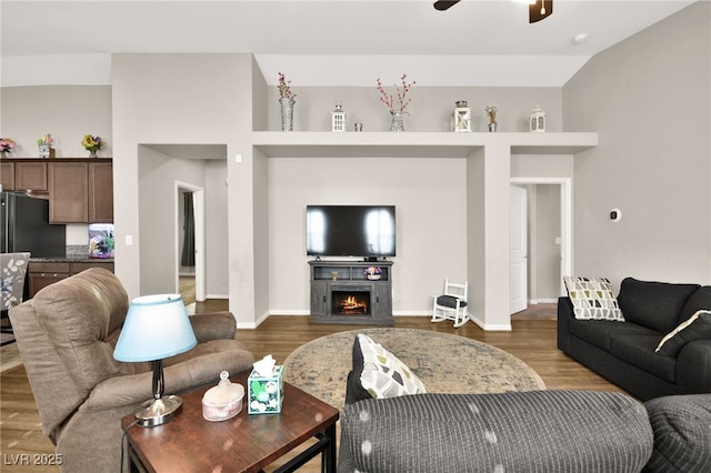 living room with ceiling fan, dark hardwood / wood-style flooring, and vaulted ceiling