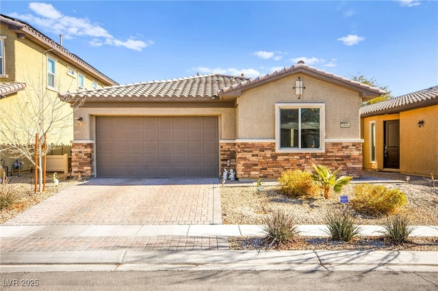 view of front of home featuring decorative driveway, stone siding, a garage, and stucco siding