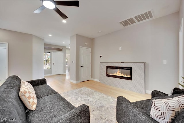 living room with baseboards, visible vents, a glass covered fireplace, wood finished floors, and recessed lighting