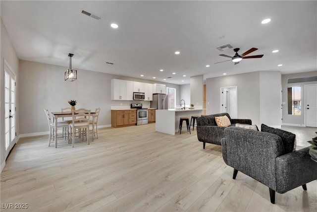 living room featuring light wood-style floors, recessed lighting, visible vents, and baseboards