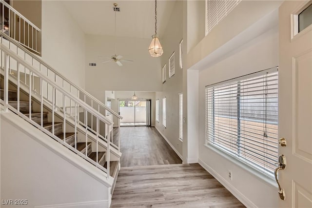 entrance foyer with a towering ceiling, ceiling fan, and wood-type flooring