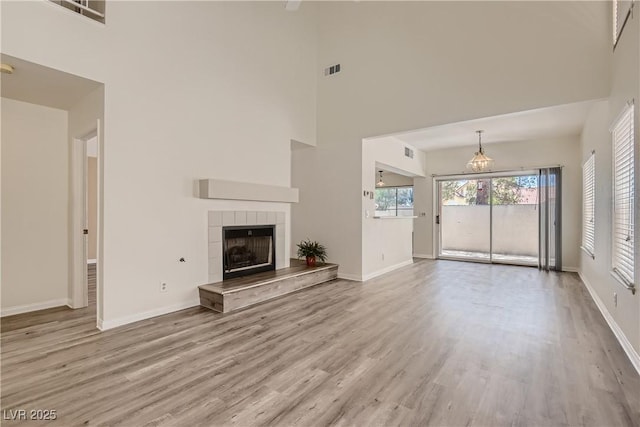 unfurnished living room with light hardwood / wood-style floors, a high ceiling, and a tile fireplace