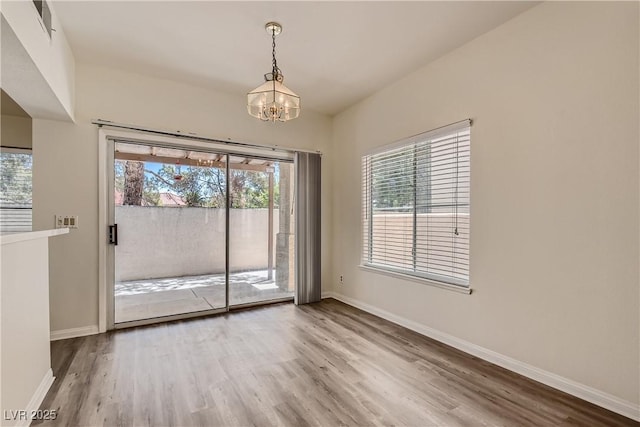 spare room with wood-type flooring and a chandelier