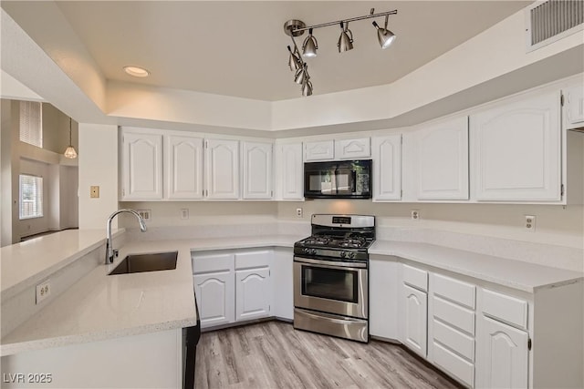 kitchen featuring kitchen peninsula, light hardwood / wood-style flooring, gas range, sink, and white cabinets