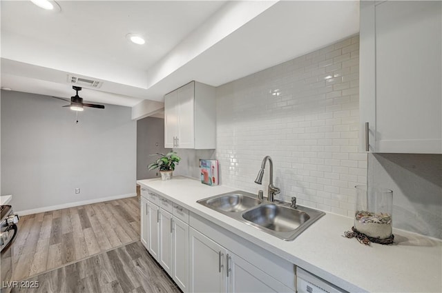 kitchen with sink, backsplash, white cabinets, and light hardwood / wood-style floors