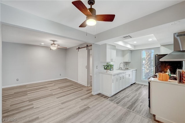 kitchen with white cabinets, a barn door, light hardwood / wood-style flooring, and sink