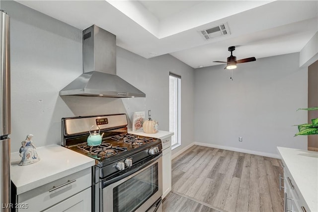 kitchen with stainless steel gas stove, light hardwood / wood-style floors, white cabinets, and range hood