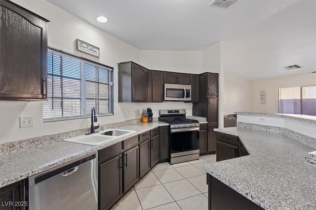 kitchen with light tile patterned floors, sink, dark brown cabinetry, stainless steel appliances, and a healthy amount of sunlight