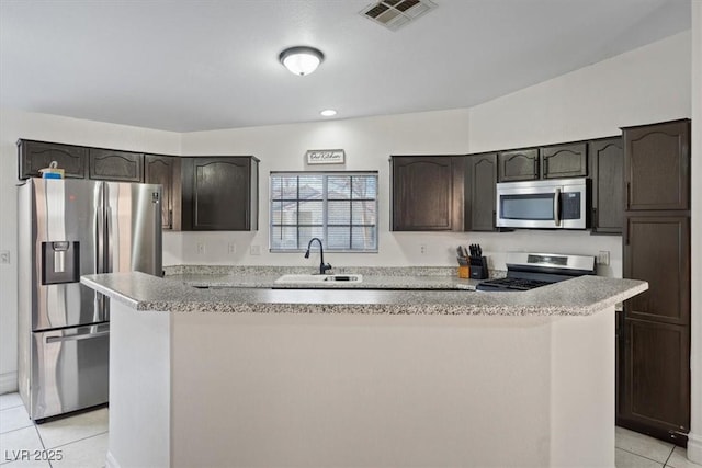 kitchen featuring sink, light tile patterned floors, stainless steel appliances, and a kitchen island